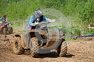 An athlete on an ATV rides through mud