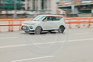 Side view of Kia Soul car in motion. White compact hatchback moving on the street
