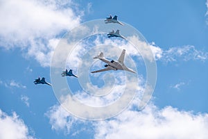 Moscow, Russia - May, 05, 2021: The Tu-160 strategic missile carrier, accompanied by four Su-35S fighter jets, flies over Red