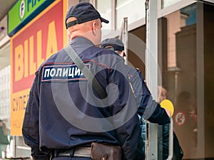 Moscow, Russia - September 14, 2019: Armed policemen enter a shopping center. Two men in police uniform open a glass shop door