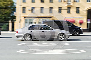 BMW E39 5-series car in the city street in motion. Old silver sedan fast speed drive on city road