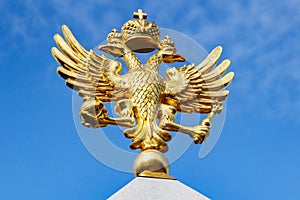 Moscow, Russia - September 13, 2019: Gilded russian double-headed eagle close-up in sunlight against blue sky. Obelisk in honor of