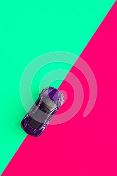 Kids toy car on trendy colorful background. Baby car top view on green and pink colored paper. Travel and sport