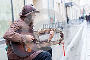 12-10-2019, Moscow, Russia. A street musician in a leather jacket and hat plays a makeshift string instrument, two necks on the