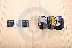 Three modern memory cards for a digital camera lie in a row on a table opposite three old 35 mm film for the camera