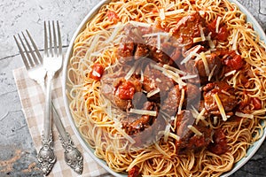 Moshari Kokkinisto or Tas Kebap Greek Veal Stew in a Tomato Sauce with pasta spaghetti closeup on the plate. Horizontal top view