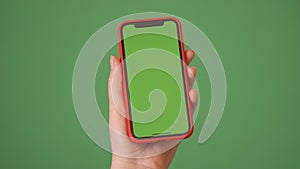 MOSKOW - MARCH 5, 2021: Phone in the hand close up isolated at green background. Phone screen is green chroma key