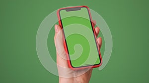 MOSKOW - MARCH 5, 2021: Phone in the hand close up isolated at green background. Phone screen is green chroma key