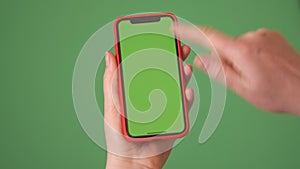 MOSKOW - MARCH 5, 2021: Phone in the hand close up isolated at green background. Phone screen is green chroma key