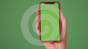 MOSKOW - MARCH 5, 2021: Phone in the hand close up isolated at green background. Phone screen is green chroma key