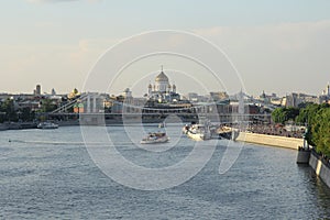 Moskva river with river buses from Novoandreevskiy Bridge. Krymsky bridge and Cathedral of Christ the Savior on the horizon in