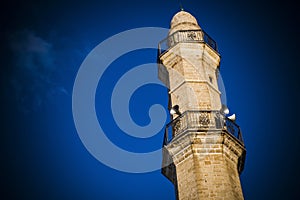 Mosque tower in strong sunlight against deep blue sky