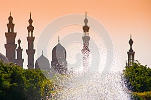 Mosques silhouettes against the yellow sky and sparkling fountain in Cairo