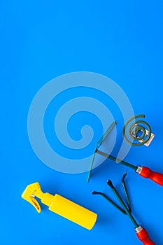 Mosquito protection for garden. Mosquito coil and spray near garden tools on blue background top view copy space