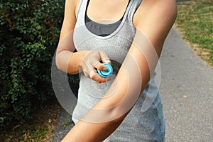 Mosquito repellent spray. Woman spraying insect repellent against bug bites on arm skin outdoor in nature forest using spray