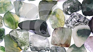 Moss agate heap jewel stones texture on white light background. Moving right seamless loop backdrop