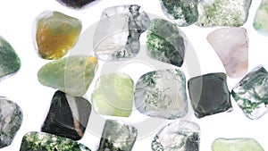 Moss agate heap up jewel stones texture on white light isolated background. Moving right seamless loop backdrop