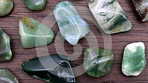 Moss agate rare jewel stones texture on brown varnished wood background. Moving right seamless loop backdrop