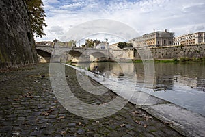 Moss covered cobbles by the river Tiber in Rome looking at one of the bridges