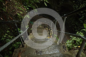 Moss-covered stairs lead to a mountain crevice with a waterfall in the jungle on the popular tourist island of Bali