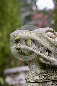 A moss-covered stone gargoyle in an Autumn garden