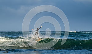 Mossel Bay, South Africa. Surfing the waves. Surfer riding wave with rainbow on storm sky background