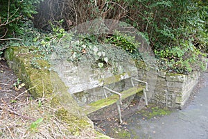 Mossy Abandoned Wooden Bench in Front of a Churchyard