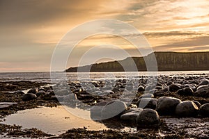 The most beautiful sunrise at Dunstanburgh Castle with the famous slippery black boulders in Northumberland, as the sky erupted wi