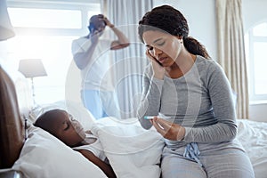 The most important thing in the world is family. a woman taking her little boys temperature with a thermometer in bed at