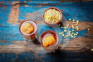 Mote con huesillo. Traditional Chilean drink made from cooked husked wheat and dried peach on wooden board, rustic blue