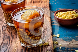 Mote con huesillo. Traditional Chilean drink made from cooked husked wheat and dried peach on wooden board, rustic blue