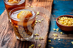 Mote con huesillo. Traditional Chilean drink made from cooked husked wheat and dried peach on wooden board, rustic blue photo
