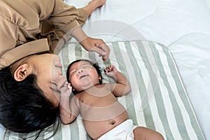 mother and 1-month-old baby newborn girl, is Half-Nigerian Half-Thai, relaxation and lying together on white bed
