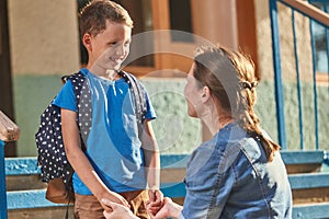 Mother accompanies the child to school. mom encourages student accompanying him to school. a caring mother looks tenderly at her