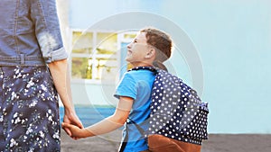 Mother accompanies the child to school. mom encourages student accompanying him to school. a caring mother looks tenderly at her