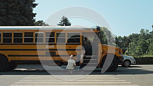 Mother accompany little son to school transport. School boy boarding yellow bus.