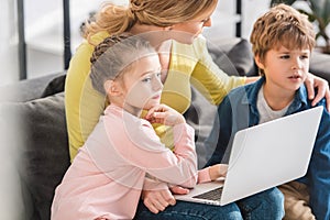 mother with adorable kids using laptop together