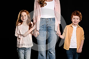 Mother with adorable redhead children standing together and holding hands