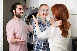 Mother and adult children standing near door and hugging at home