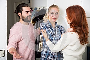 Mother and adult children standing near door and hugging at home