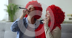 Mother and adult daughter blowing party horns celebrate life event