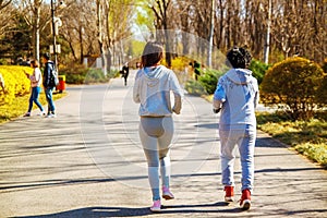 Mother and adult daughter running for sport in park for better fitness.