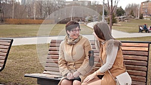 Mother and adult daughter spend time together outdoors in the Park, chatting and laughing