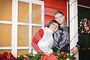 Mother and adult son near red wall of the house decorated for Ch