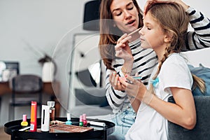 Mother applies eye shadow to her daughters eyelids photo