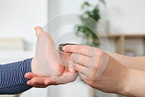 Mother applying essential oil from roller bottle onto her baby`s heel indoors, closeup