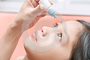 mother applying eye drops to her daughter because of eye irritation