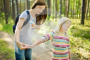 Mother applying insect repellent to her daughter before forest hike summer day. Protecting children from biting insects at summer