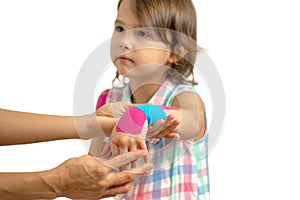 Mother applying kinisiology tape to her daughter injury hand