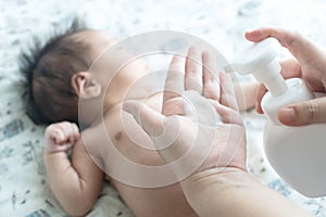 Mother are applying a lotion cream on the baby body after bath